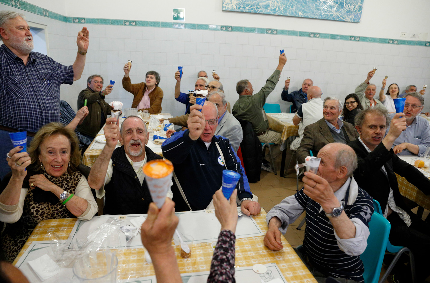 People raise their ice cream cones donated by Pope Francis as they toast the Pope at a Sant’Egidio soup kitchen in Rome April 23. In honor of his name day, the feast of St. George, the Pope donated 3,000 servings of ice cream to soup kitchens and homeless shelters around Rome.